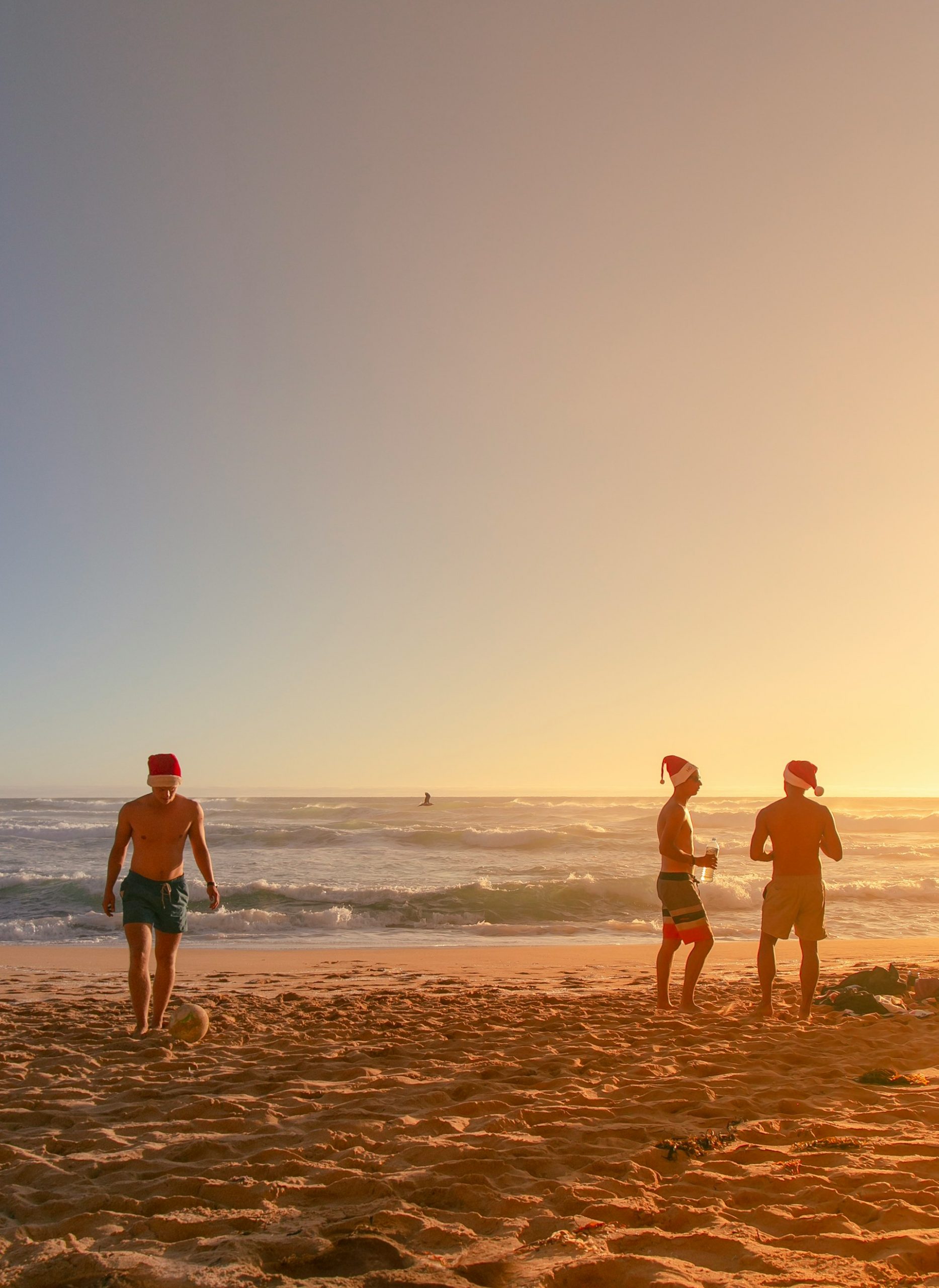 Eine Gruppe von Menschen mit Nikolaus-Mützen auf einem Sandstrand im Abendlich